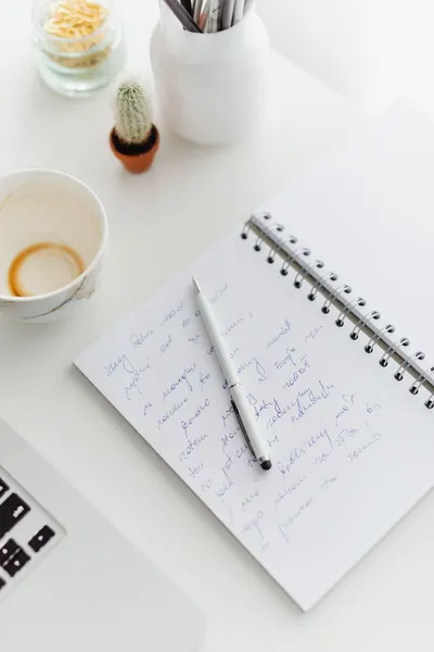 Top view of a workspace with notebook, pen, and empty coffee cup for idea generation.