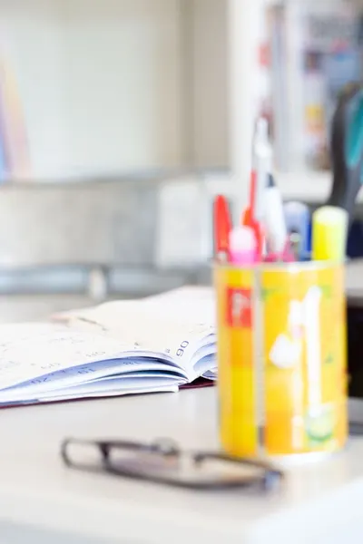 Blurred journal, eyeglasses, and colorful stationery on a tidy desk.