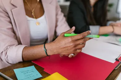 Professional setting with diverse hands holding pens during a business meeting.