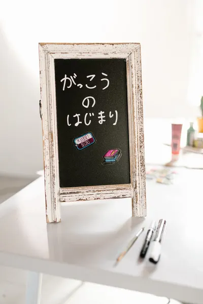 Japanese chalkboard sign on a desk with art supplies. Ideal for schools or creative themes.