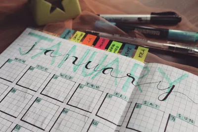 Handwritten January planner page with tags and pens on a desk. Perfect for organizing schedules.