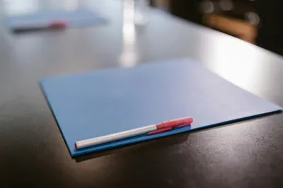Close-up of a blue folder and pen on a table in a modern office environment.