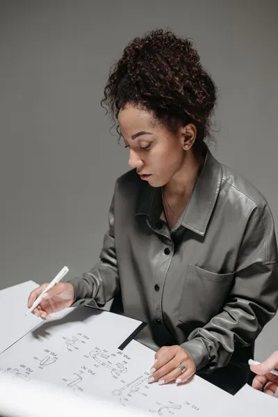 African American woman with curly hair reviewing documents at a desk in an indoor setting.
