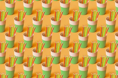 Vibrant assortment of colored pencils in eco-friendly paper cups arranged in a geometric pattern.