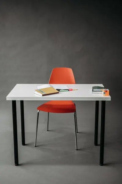 A minimalist office setup featuring a red chair and a white desk, ideal for modern workplaces.