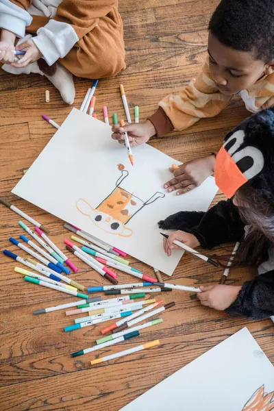 Kids in animal costumes enjoying a creative drawing session on the floor.