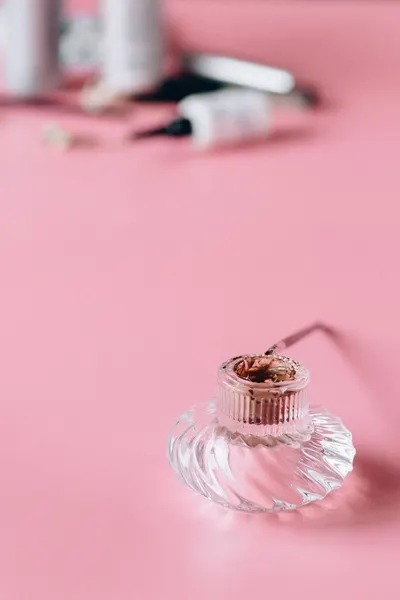 Close-up of a glass perfume bottle on a pink surface, showcasing beauty and elegance.