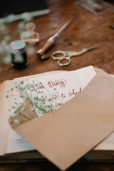 Close-up of a diary entry with calligraphy and an envelope on a rustic table.