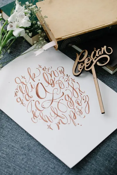 Artistic handwritten calligraphy on paper with flowers and book for creative inspiration.