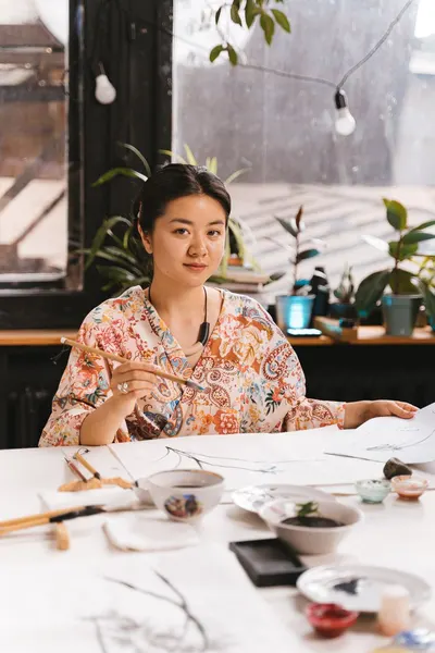 A woman practicing traditional art techniques in a cozy studio setting.
