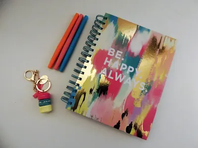 Flat lay of vibrant stationery with a motivational notebook and keychain.