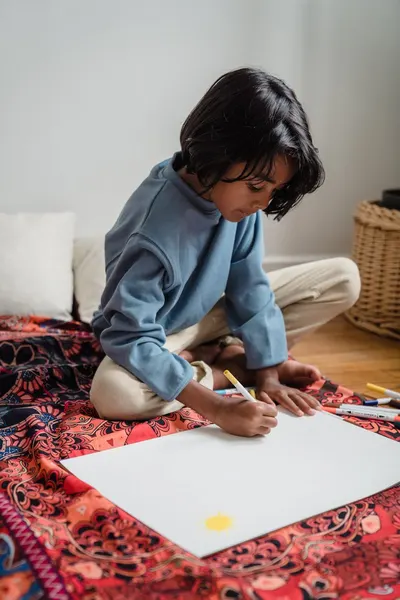 A child focused on drawing with pencils in a cozy indoor setting, showcasing creativity.