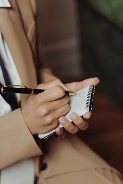 Close-up of a hand writing notes in a notepad, ideal for business or study themes.