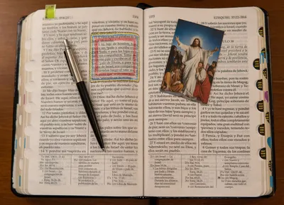 An open Bible with an image of Jesus and a pen emphasizes Christianity study.