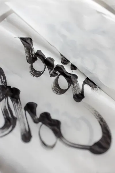 Close-up of elegant black ink calligraphy on white paper, showcasing intricate hand lettering.