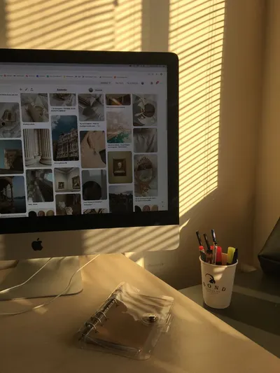 Sunlight streaming through blinds onto a desk with a computer and office supplies in a cozy workspace.