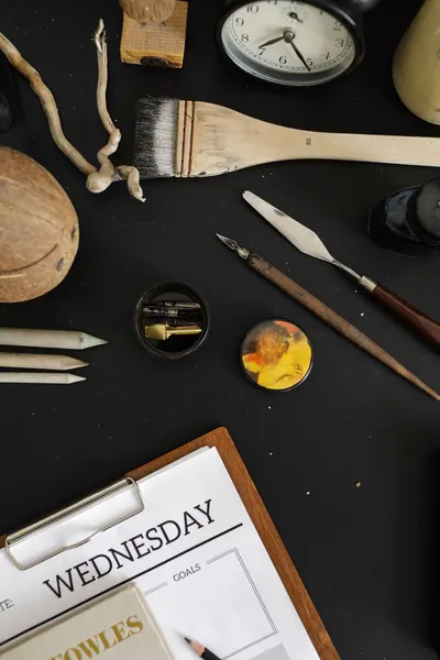 An artistic flat lay with various creative supplies including a brush and fountain pen.